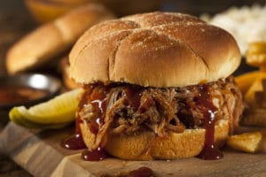 barbeque pulled pork sandwich with a pickle and fries